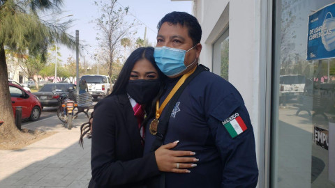 Sorprende a su padre con título y medalla de excelencia 