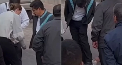 Exhiben a Hugo Aguilar mientras asistentes le limpian los zapatos en acto oficial