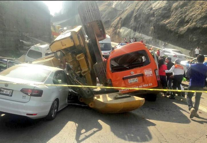 Retroexcavadora cae aplastando vehículos